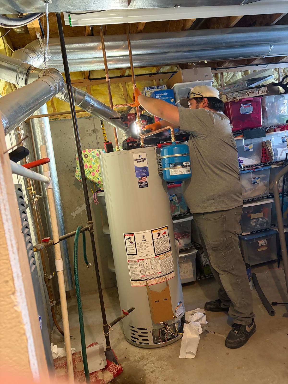 Technician connecting copper piping above a Bradford White water heater