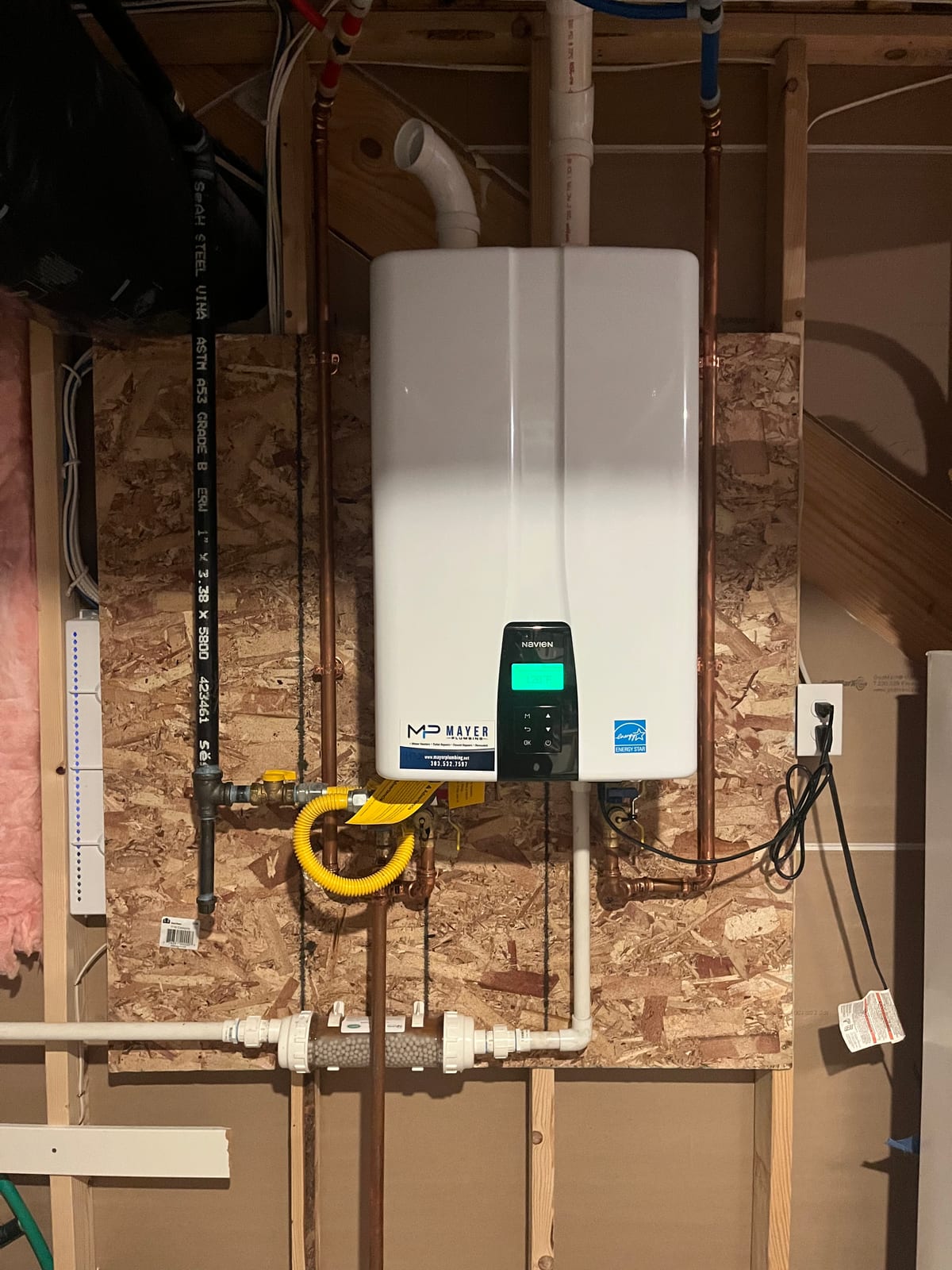 Installed Navien tankless water heater with Mayer Plumbing service label