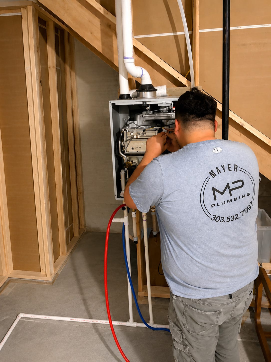 Mayer Plumbing technician servicing a tankless water heater with its cover removed