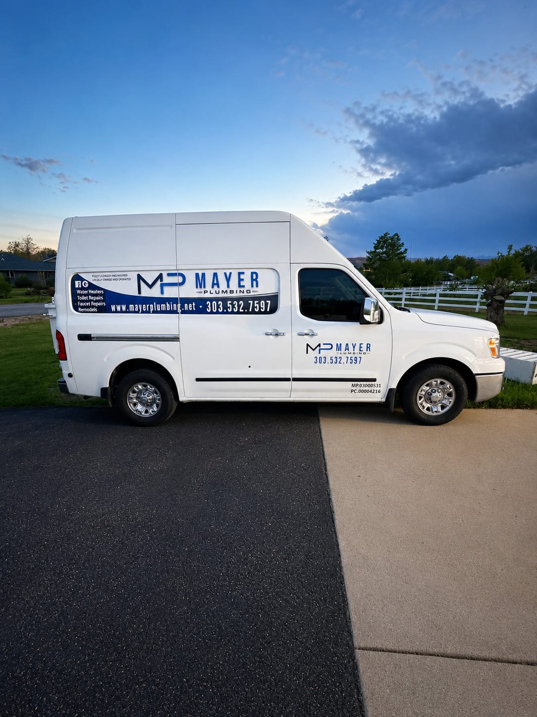 Mayer Plumbing service van parked beside a driveway at dusk
